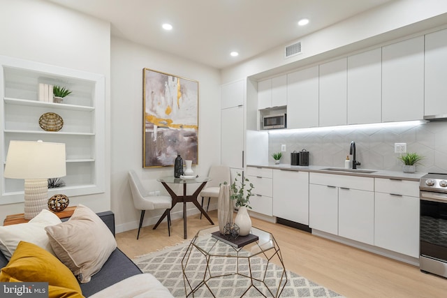 living room with built in features, light hardwood / wood-style floors, and sink