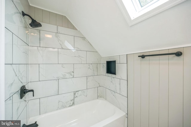 bathroom featuring a skylight and tiled shower / bath