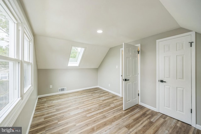 additional living space with light hardwood / wood-style floors and vaulted ceiling with skylight