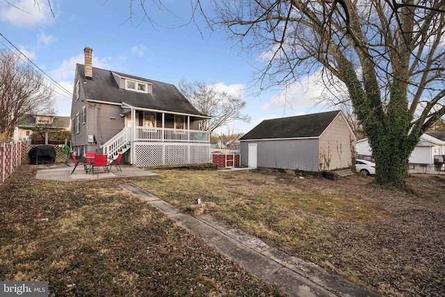 back of property with a lawn, a patio area, and a storage shed