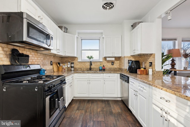 kitchen with white cabinetry, appliances with stainless steel finishes, dark wood-type flooring, and light stone counters