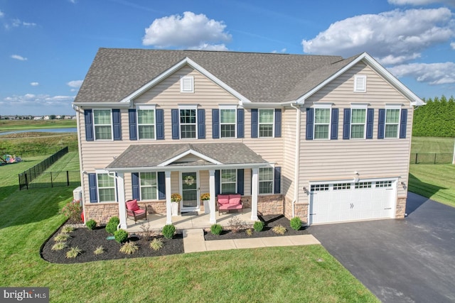 view of front of property featuring a garage, a porch, and a front lawn