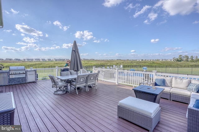 wooden terrace with exterior kitchen, an outdoor hangout area, a fenced in pool, and a grill