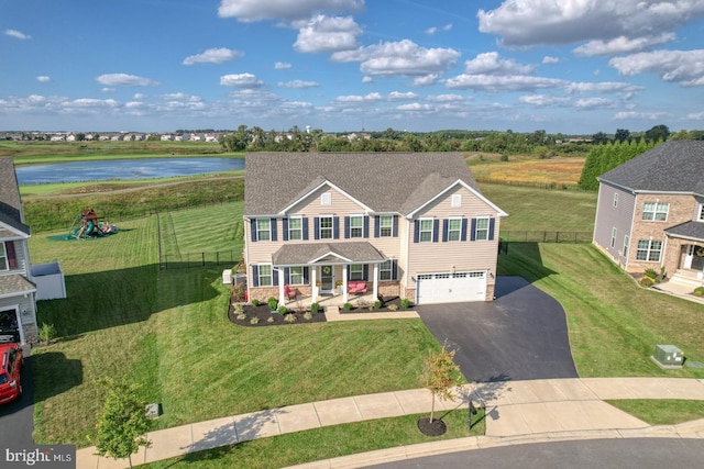 view of front of property featuring a playground, a front lawn, a garage, and a water view