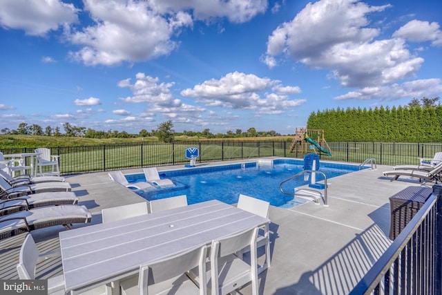 view of swimming pool featuring a patio and a playground