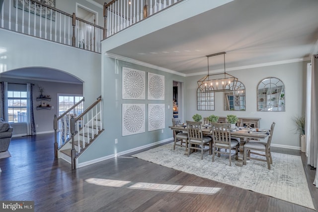 dining room featuring a high ceiling, a notable chandelier, crown molding, and dark wood-type flooring