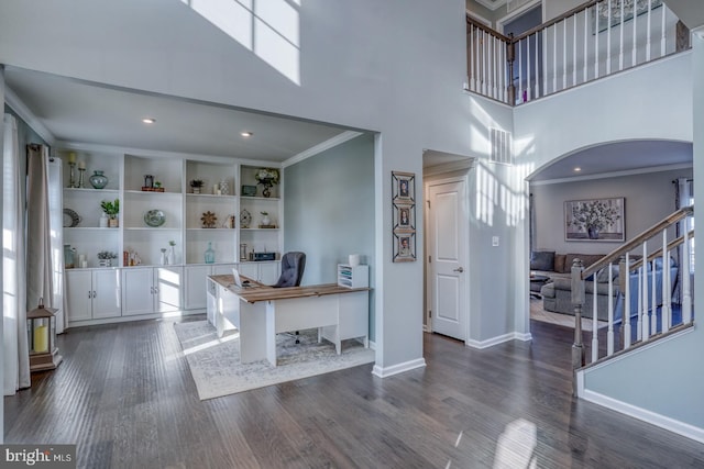 foyer with a towering ceiling, ornamental molding, and dark hardwood / wood-style floors