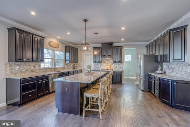 kitchen with appliances with stainless steel finishes, a center island, pendant lighting, sink, and dark brown cabinets