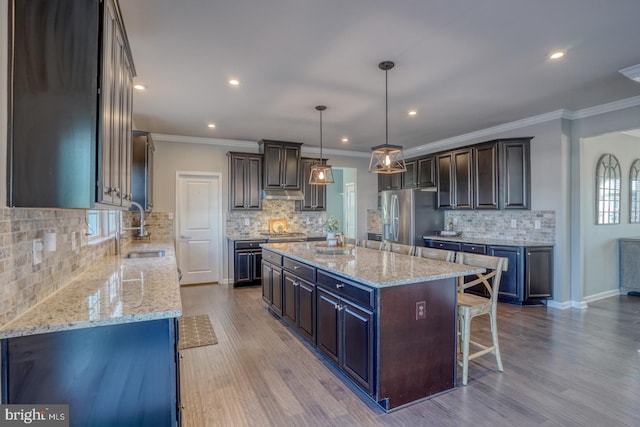 kitchen featuring sink, a kitchen island, dark brown cabinets, and stainless steel fridge