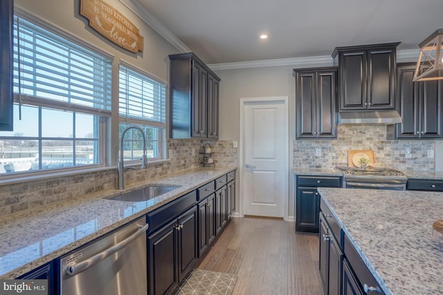 kitchen with sink, light hardwood / wood-style floors, backsplash, light stone countertops, and appliances with stainless steel finishes