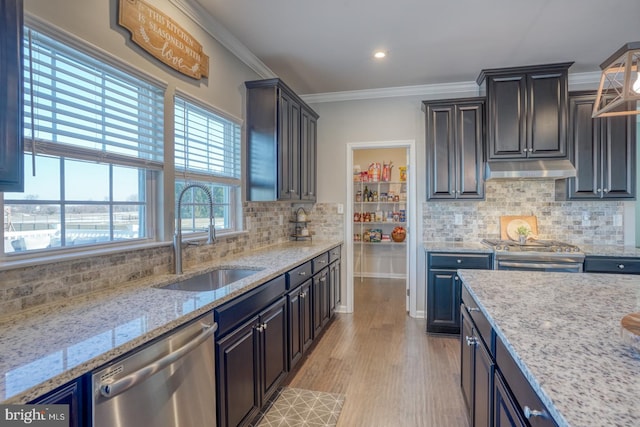 kitchen with sink, light stone counters, light wood-type flooring, backsplash, and appliances with stainless steel finishes