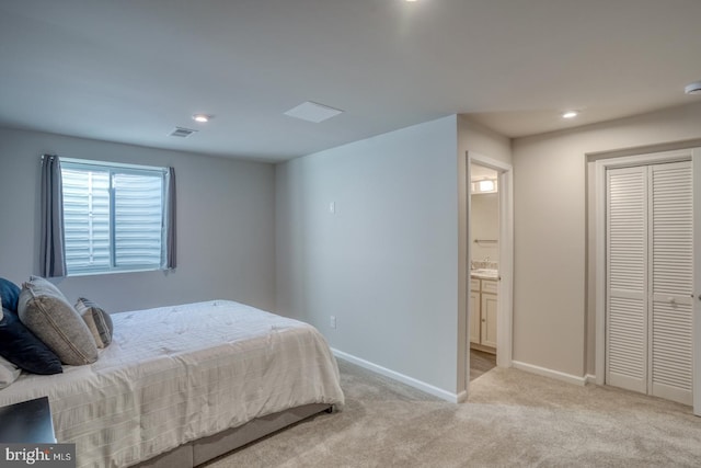 bedroom with connected bathroom, a closet, and light carpet