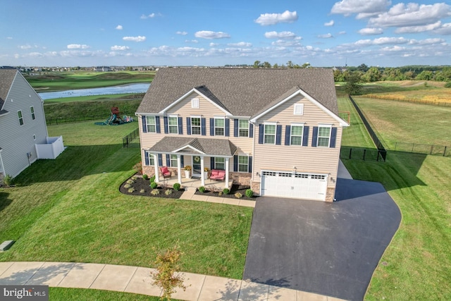 view of front of property with covered porch, a front lawn, a garage, and a water view