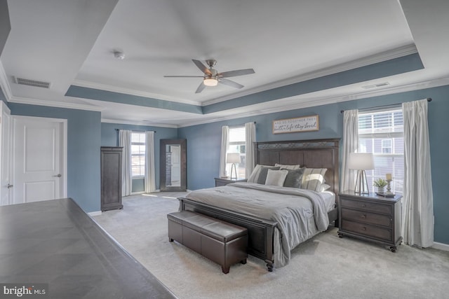 bedroom featuring ceiling fan, light carpet, and a tray ceiling