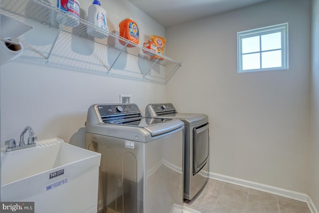 laundry room featuring light tile patterned floors, washer and clothes dryer, and sink