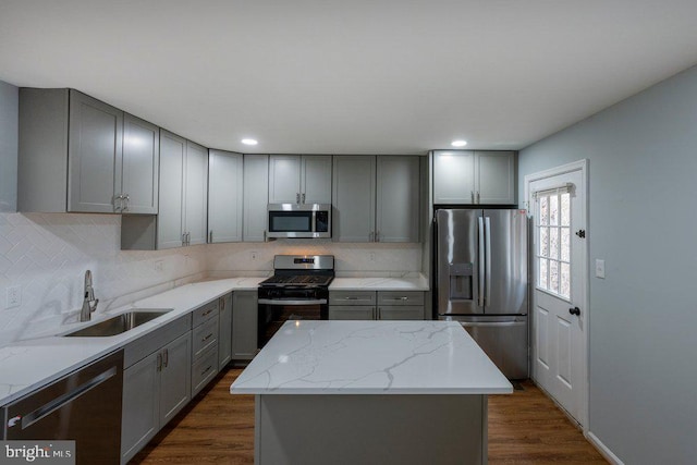 kitchen with stainless steel appliances, sink, a kitchen island, and gray cabinetry