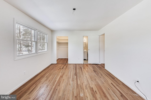 unfurnished bedroom with a walk in closet, a closet, and light hardwood / wood-style flooring