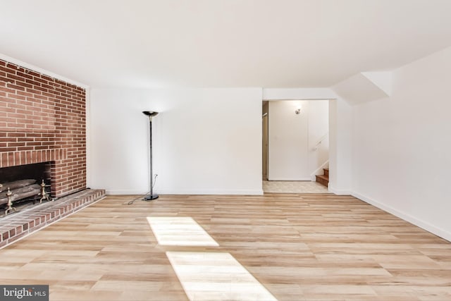 unfurnished living room featuring a brick fireplace and light wood-type flooring