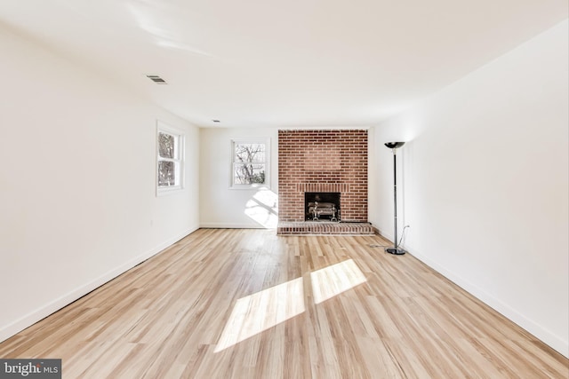 unfurnished living room with a brick fireplace and light hardwood / wood-style floors