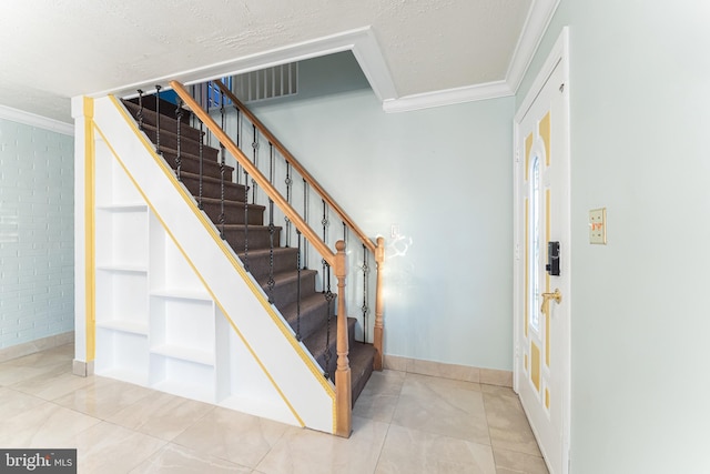 tiled foyer featuring a textured ceiling and ornamental molding