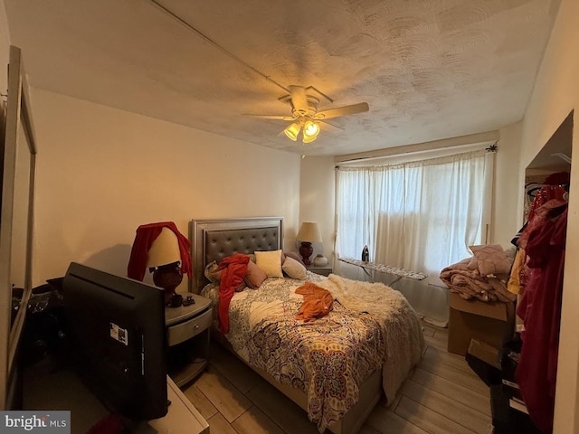 bedroom featuring ceiling fan, light hardwood / wood-style flooring, and a textured ceiling