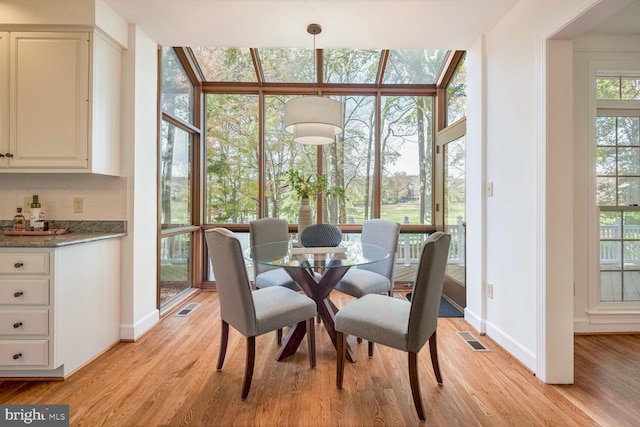 dining area with light hardwood / wood-style floors, a wealth of natural light, and expansive windows