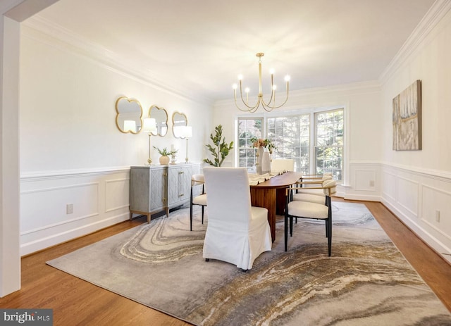 dining space featuring wood-type flooring, an inviting chandelier, and ornamental molding