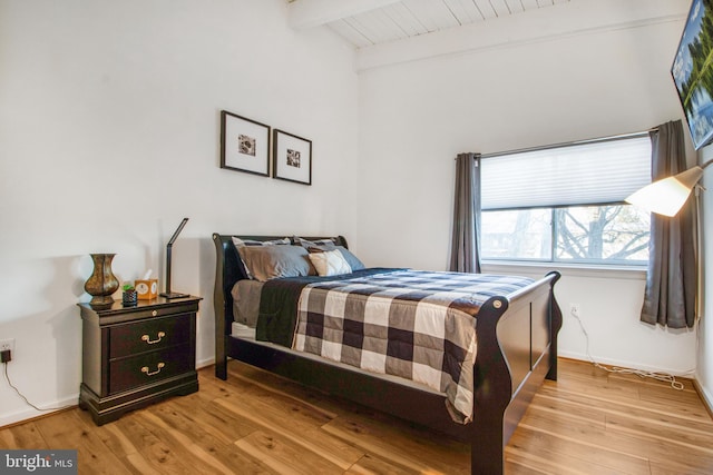 bedroom with beam ceiling, wood ceiling, and light hardwood / wood-style floors