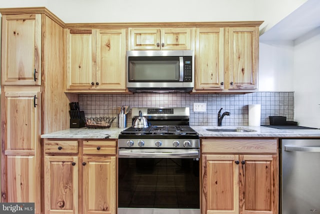 kitchen with decorative backsplash, sink, light stone counters, and stainless steel appliances