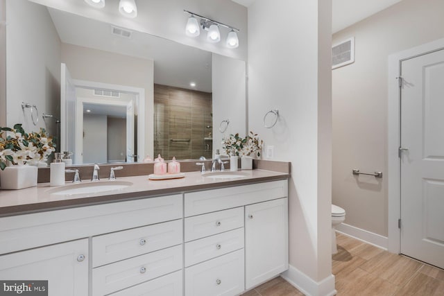 bathroom featuring toilet, vanity, and a shower with shower door