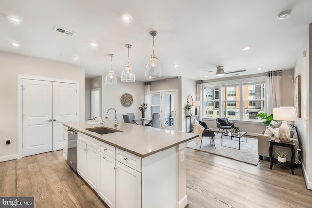 kitchen with white cabinets, a kitchen island with sink, dishwasher, and sink