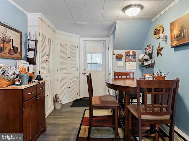 dining space featuring dark wood-type flooring, crown molding, and baseboard heating