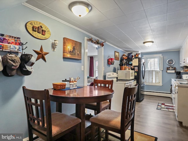 dining area with washer / dryer, a baseboard radiator, crown molding, and wood-type flooring