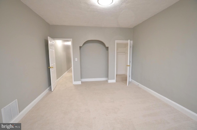 unfurnished bedroom with a textured ceiling, a closet, and light carpet