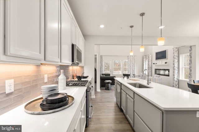 kitchen with sink, white cabinets, decorative light fixtures, a kitchen island with sink, and appliances with stainless steel finishes