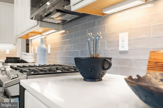 kitchen with white cabinets, backsplash, range hood, and gas stovetop