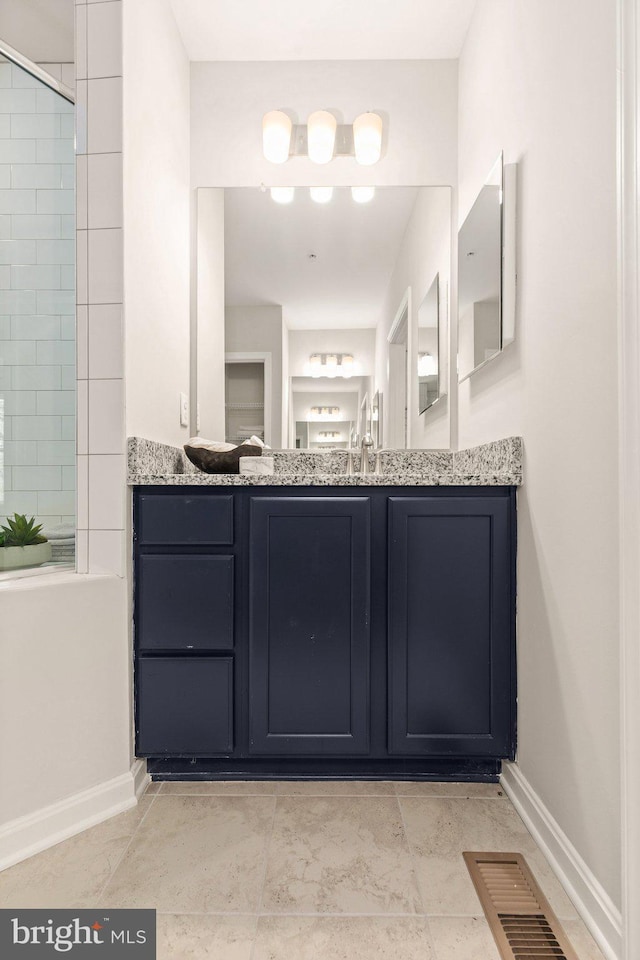 bathroom with a tile shower, vanity, and tile patterned floors