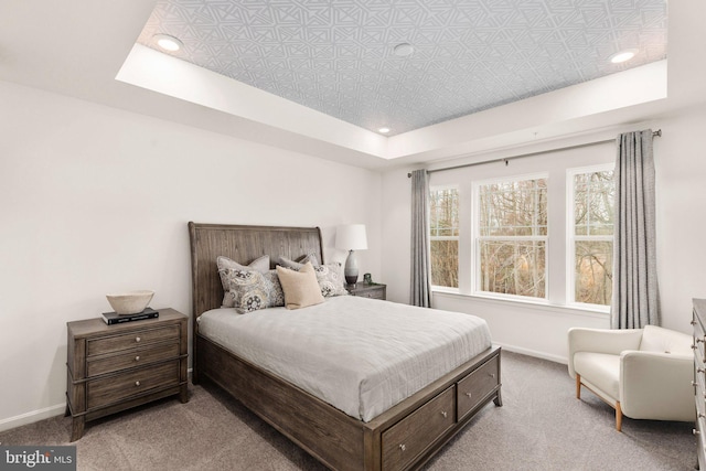 carpeted bedroom with a tray ceiling