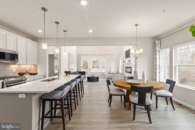 dining room featuring a fireplace, light wood-type flooring, a chandelier, and sink