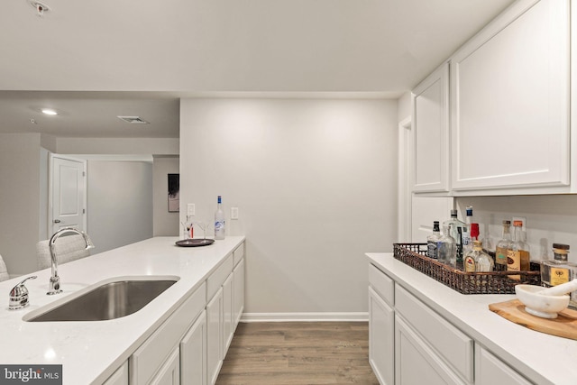 kitchen with sink, white cabinets, and wood-type flooring