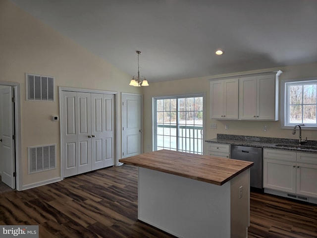 kitchen with white cabinets, a center island, wood counters, sink, and stainless steel dishwasher