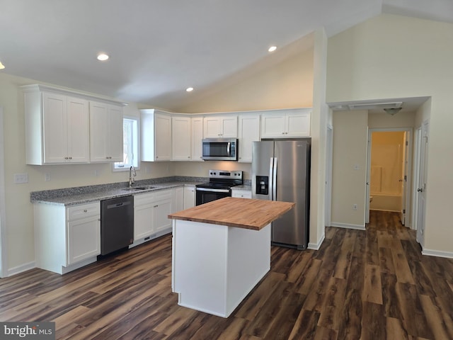 kitchen with white cabinets, appliances with stainless steel finishes, a center island, sink, and dark hardwood / wood-style floors