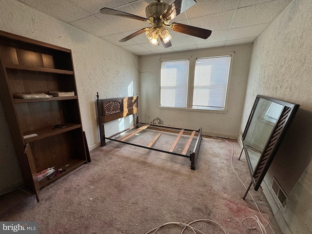 bedroom featuring ceiling fan, carpet floors, and a drop ceiling