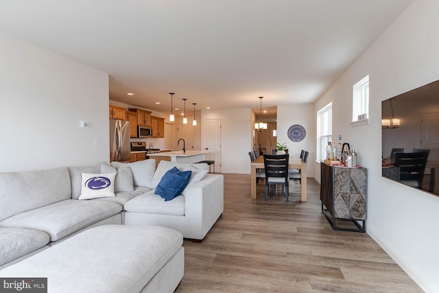 living room featuring sink, an inviting chandelier, and light hardwood / wood-style floors