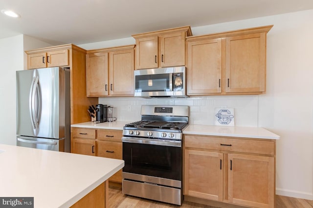 kitchen featuring tasteful backsplash, light brown cabinets, stainless steel appliances, and light hardwood / wood-style floors