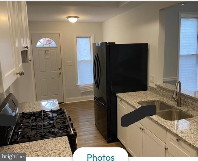 kitchen featuring black appliances, dark wood-type flooring, light stone counters, white cabinets, and sink