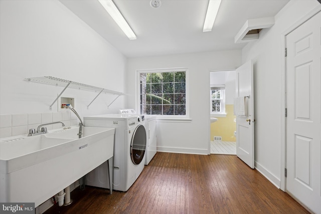 laundry room featuring washer and dryer, a sink, dark wood finished floors, baseboards, and laundry area