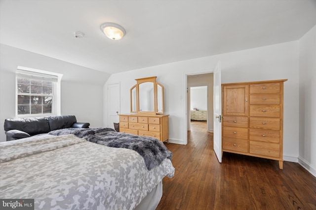 bedroom with dark wood-type flooring, baseboards, and vaulted ceiling