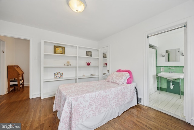 bedroom featuring a sink, visible vents, tile walls, and wood finished floors