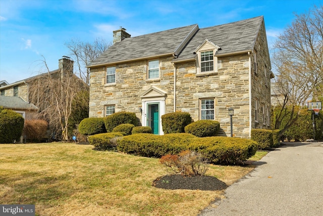 view of front of house featuring a chimney and a front yard